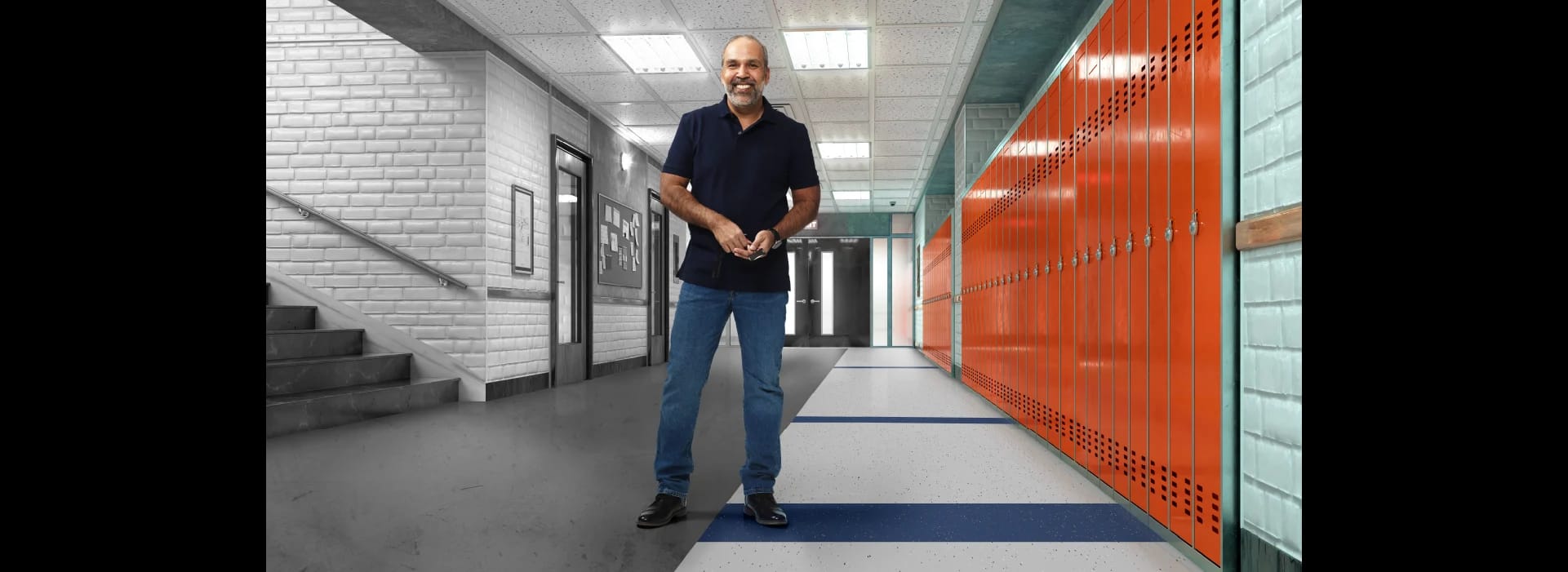 A smiling flooring contractor stands centered in a school hallway – old flooring is on the left; new flooring is at right.