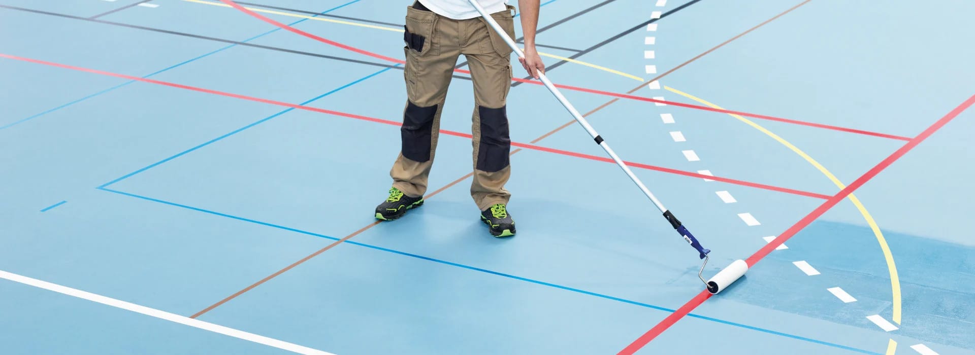 A flooring professional rolls a Bona SuperCourt finish onto a sport floor, giving it a protective coating and a new look.