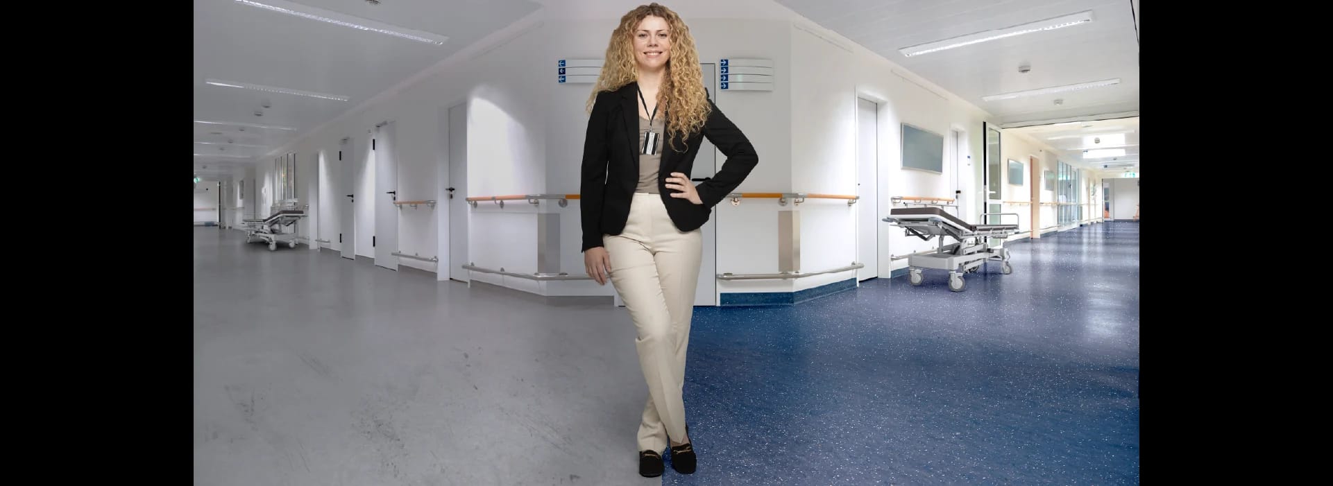 A hospital facility manager stands between two hallways. The left has old flooring; the right has new resilient flooring.