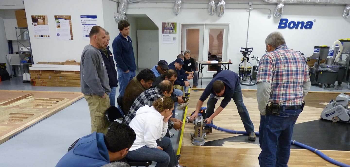 A Bona instructor gives a classroom demonstration of edge sanding before a group of Bona Certified Craftsmen-in-training.