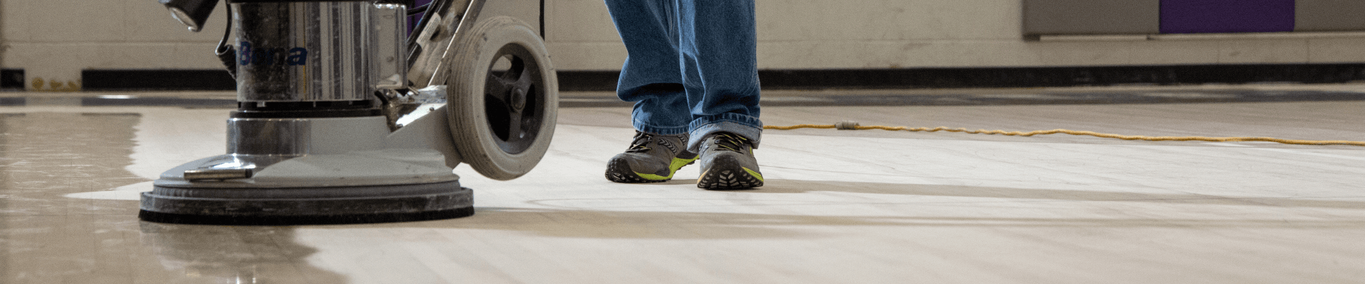 A flooring professional uses a Bona Power Drive to abrade the coating of a wood floor to prepare for a new coat of finish.