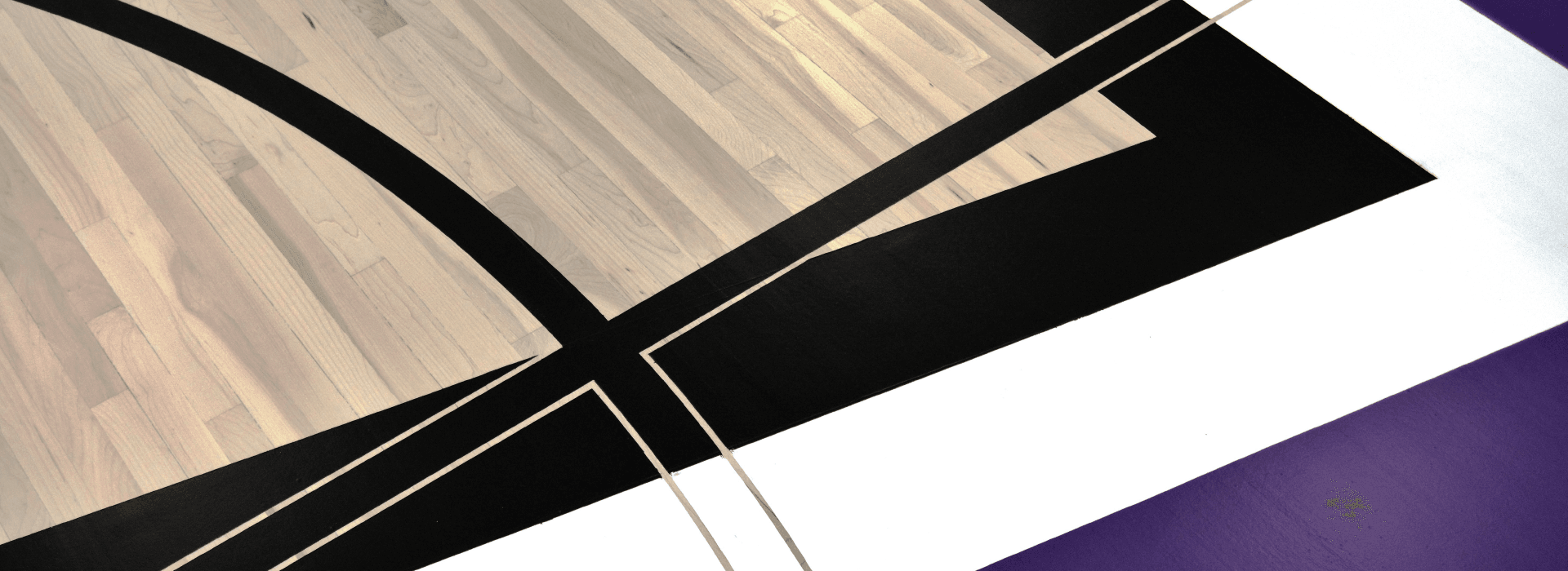 A section of a beautiful maple hardwood pro sport floor, featuring team graphics and Bona waterborne game line paint.