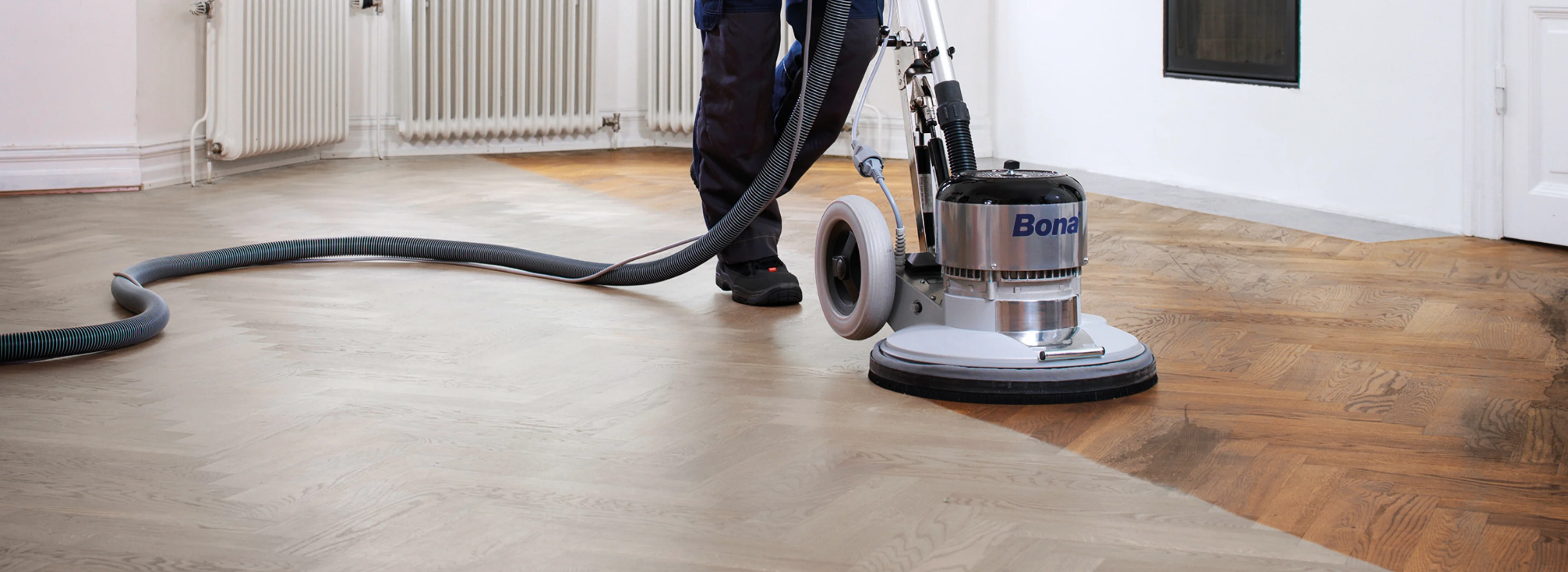 A flooring professional is sanding a hardwood floor with the Bona Power Drive to create a beautifully even surface.